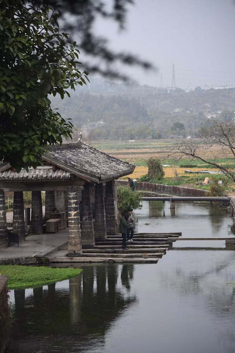 Old stone pavilion beside a quiet canal in Heshun Ancient Town